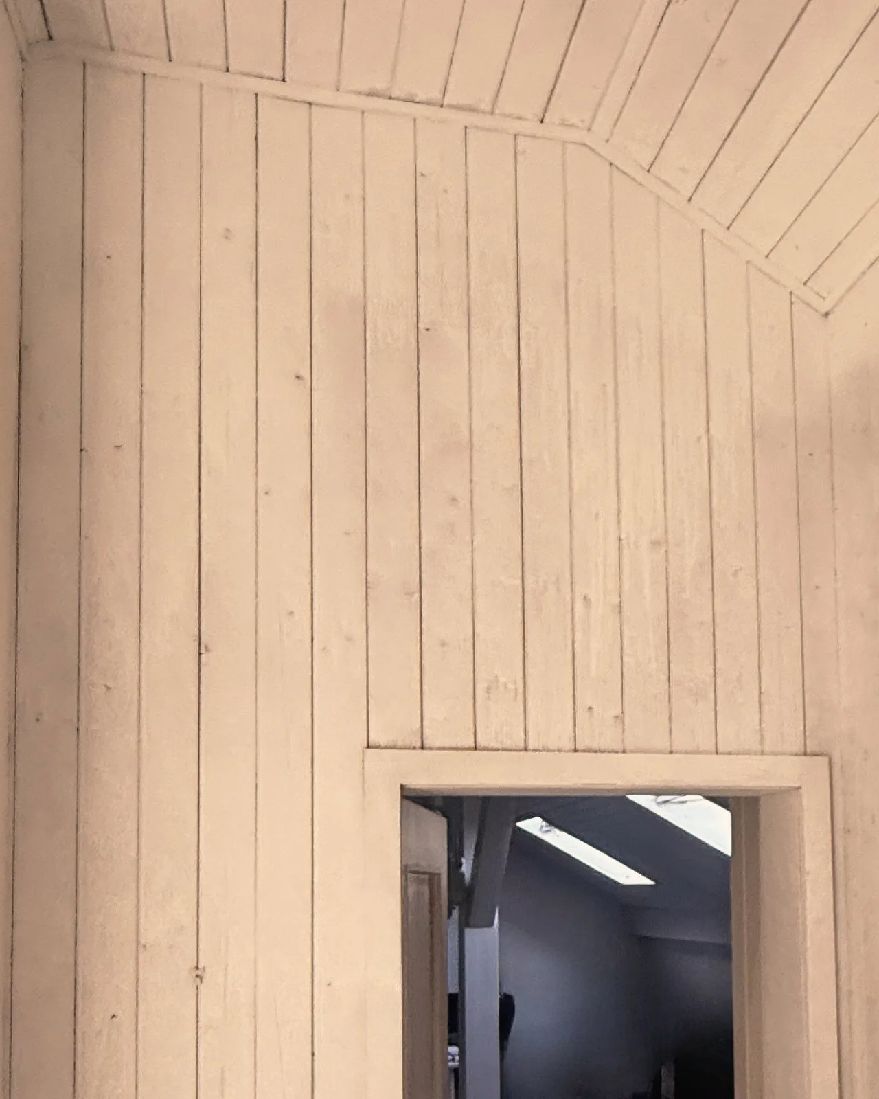 Pignon en lambris peint en blanc au-dessus de la porte vitrée, après les travaux
